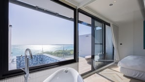 Ein modernes Badezimmer mit großem Fenster, einer Badewanne und Meerblick.