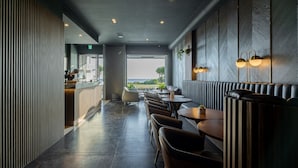 Ein modernes Restaurant mit einer langen Theke, Sitzgelegenheiten und Blick ins Freie.