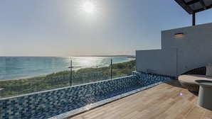 Ein moderner Poolbereich im Freien mit Blick auf den Ozean, einer gefliesten Terrasse und einer Lounge-Ecke.