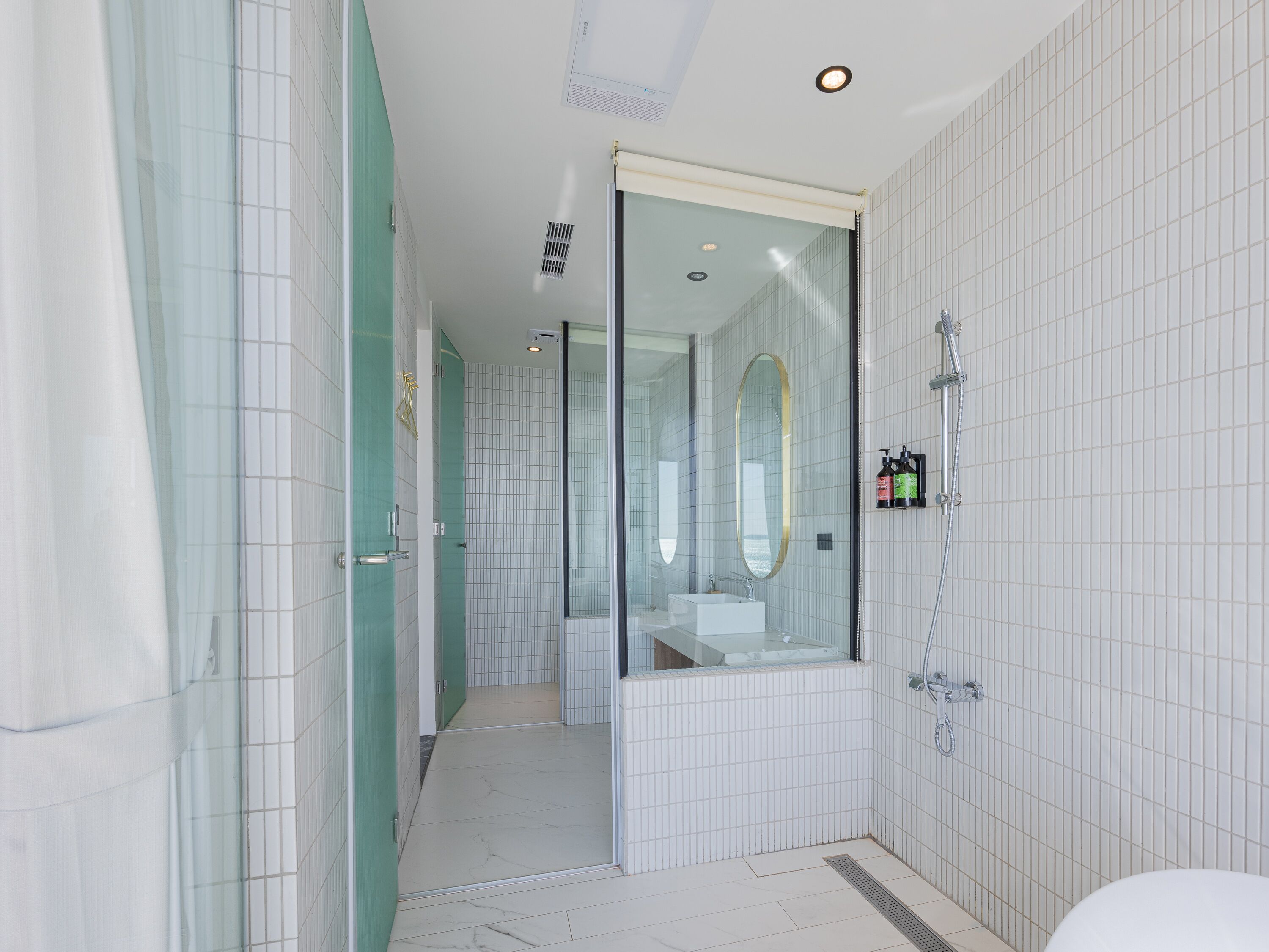 A modern bathroom with a glass shower enclosure, a white sink, and a mirror.