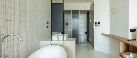 Un baño moderno con una bañera independiente, un banco de madera y una repisa de madera con toallas.
