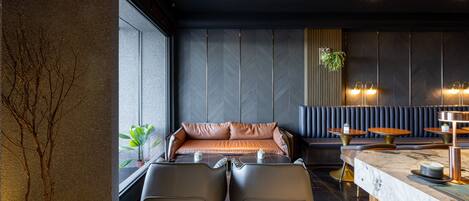 Un interior moderno con un sofá, dos sillones, una zona de bar y una planta en maceta.