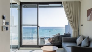 Ein modernes Wohnzimmer mit einer Couch, einem Couchtisch und Blick auf den Ozean durch große Schiebeglasfenster.