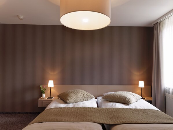 Relax in a serene space with a large bed, bedside lamps, and a neutral-toned wall.