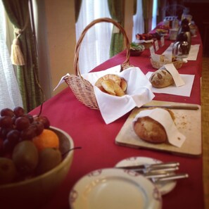 Guests can enjoy a delicious meal at this dining table, set with a variety of food items, including fresh fruit and baked goods.