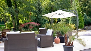 An outdoor seating area with wicker furniture and a large umbrella. - Hotel Kurparkblick (Bad Bergzabern)
