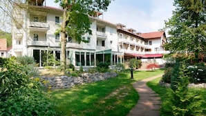 A multi-story hotel with a garden pathway leading to the entrance. - Hotel Kurparkblick (Bad Bergzabern)