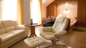 A modern living room with a sofa, armchair, ottoman, and a small round table. - Hotel Kurparkblick (Bad Bergzabern)