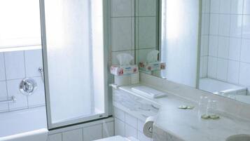 A bathroom with a toilet, a sink, a mirror, and a shower.