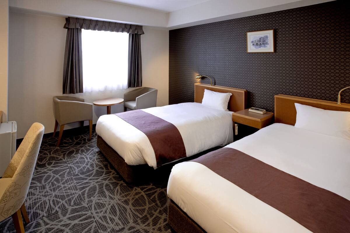 Een hotelkamer met twee bedden, een bureau en een stoel.