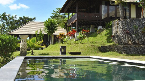 Un área de piscina con un muro de piedra y una terraza de madera.