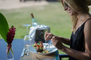 Una mesa de comedor con un plato de comida, un vaso de agua y una botella de vino.