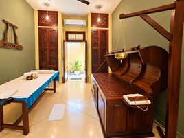 A spa room with a massage table, wooden cabinets, and a hanging massage chair.