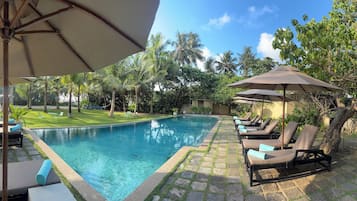 Una piscina al aire libre, sillones reclinables de piscina