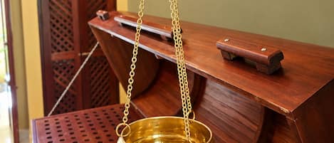 Una lámpara de aceite de bronce colgando de una estructura de madera con una base de metal perforado.