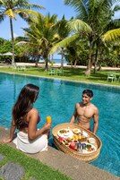 A poolside scene with a dining setup featuring a basket of food and drinks.