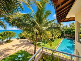 Vista de la piscina con una clara vista del océano, una palmera y un pequeño bote.