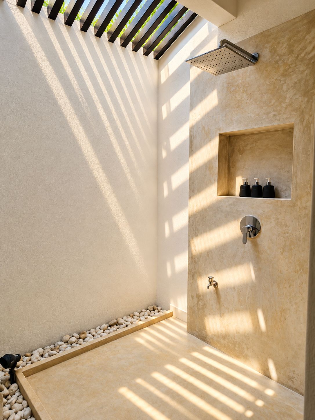 Un baño moderno con ducha, estante de artículos de aseo y un borde de guijarros.