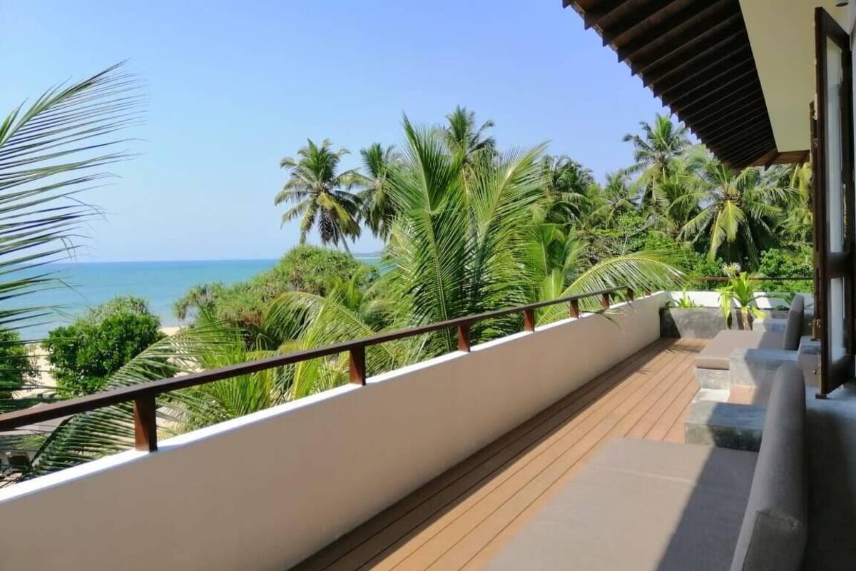 A balcony with a view of the ocean and palm trees.