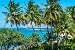 A tropical beach with palm trees and a clear blue sea. - Aavya Cove Villas By Aahaasa (Balapitiya)