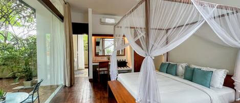 A bedroom with a canopy bed, a desk, and a view of the outdoors.