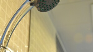 A showerhead with multiple round nozzles, mounted on a chrome arm.