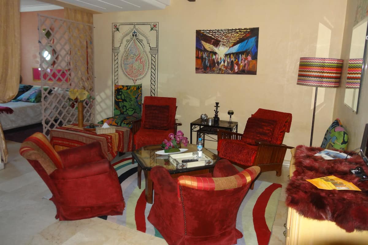 Uma sala de estar com cadeiras vermelhas, um sofá, uma mesa de centro e um quadro na parede.