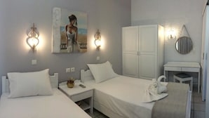 Une chambre d’hôtel avec deux lits simples, une table de chevet avec une lampe, un miroir et un tableau au mur.