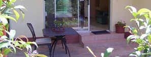 An outdoor patio with a table and chairs, a potted plant, and a sliding glass door leading to an interior space. - Ascot Gardens Self Catering (Cape Town)
