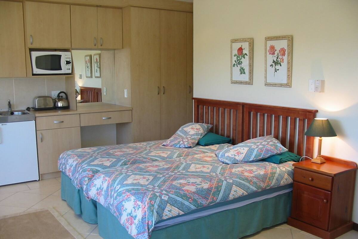 Une chambre à coucher de taille réduite, comprenant un lit, une table de chevet et un petit coin cuisine.