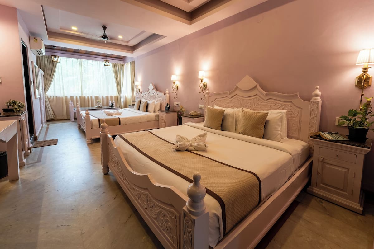 Una habitación de hotel con una cama grande, una cama más pequeña, un escritorio y una tocador.