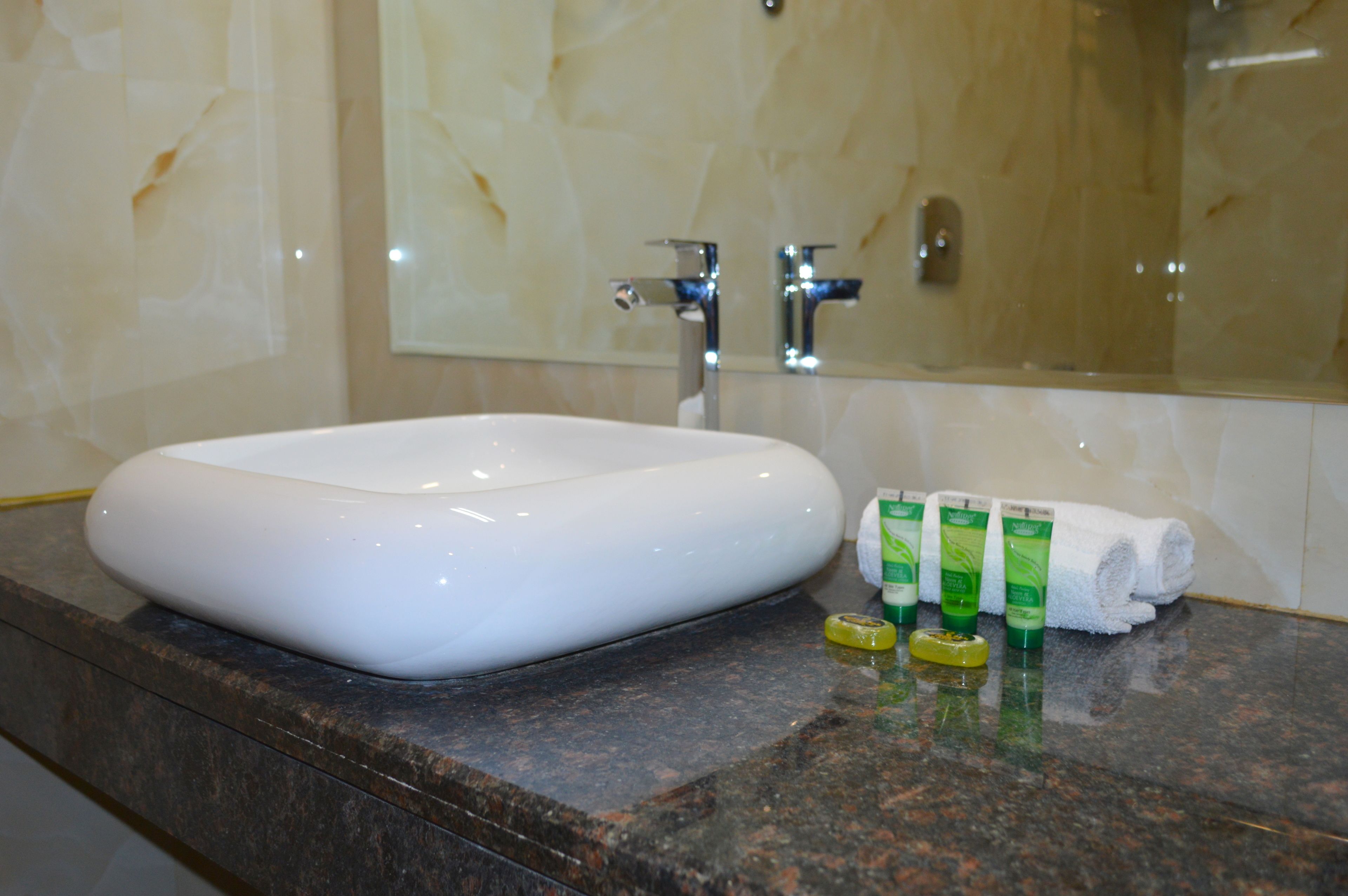 A bathroom with a white sink, marble walls, and a mirror.