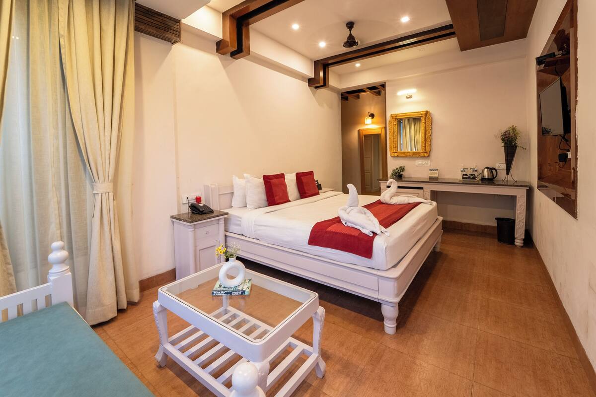 Una habitación de hotel con cama, mesita de noche y una pequeña mesa blanca con un florero.
