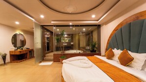 Habitación de hotel moderna con una cama grande, un espejo redondo, una consola de madera y vistas a un área de spa.