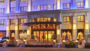 A hotel entrance with a grand archway, large windows, and a well-lit facade.