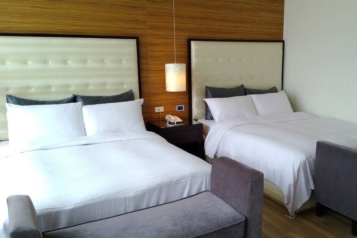 Une chambre d’hôtel avec deux lits, une table de chevet avec un téléphone et un petit coin salon.