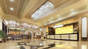 A spacious lobby with a central seating area, a reception desk, and a decorative chandelier.