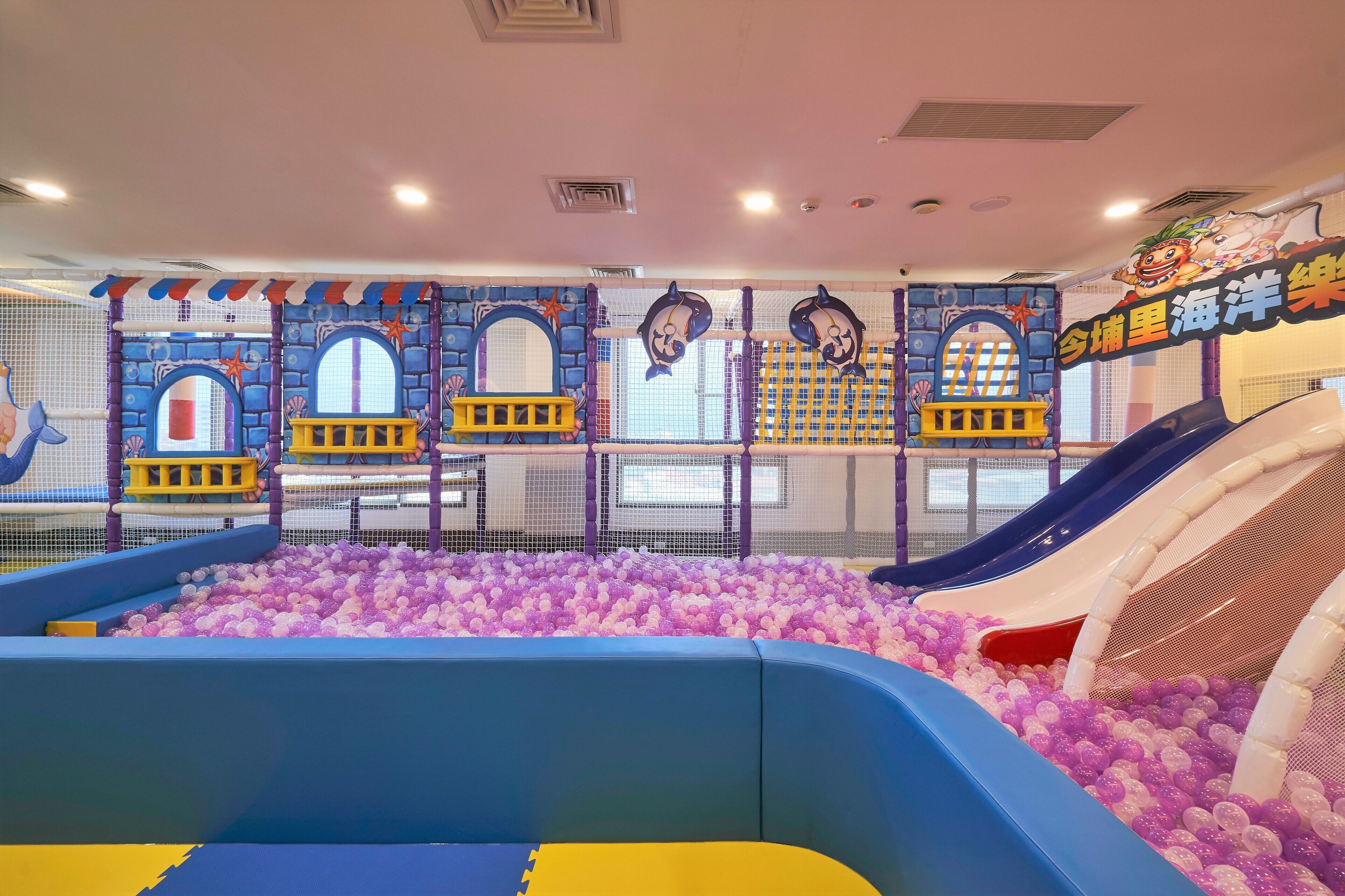 An indoor play area with a ball pit, slides, and a netted play structure.