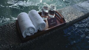 A spa area with a hot tub, towels, and glasses on a tray.