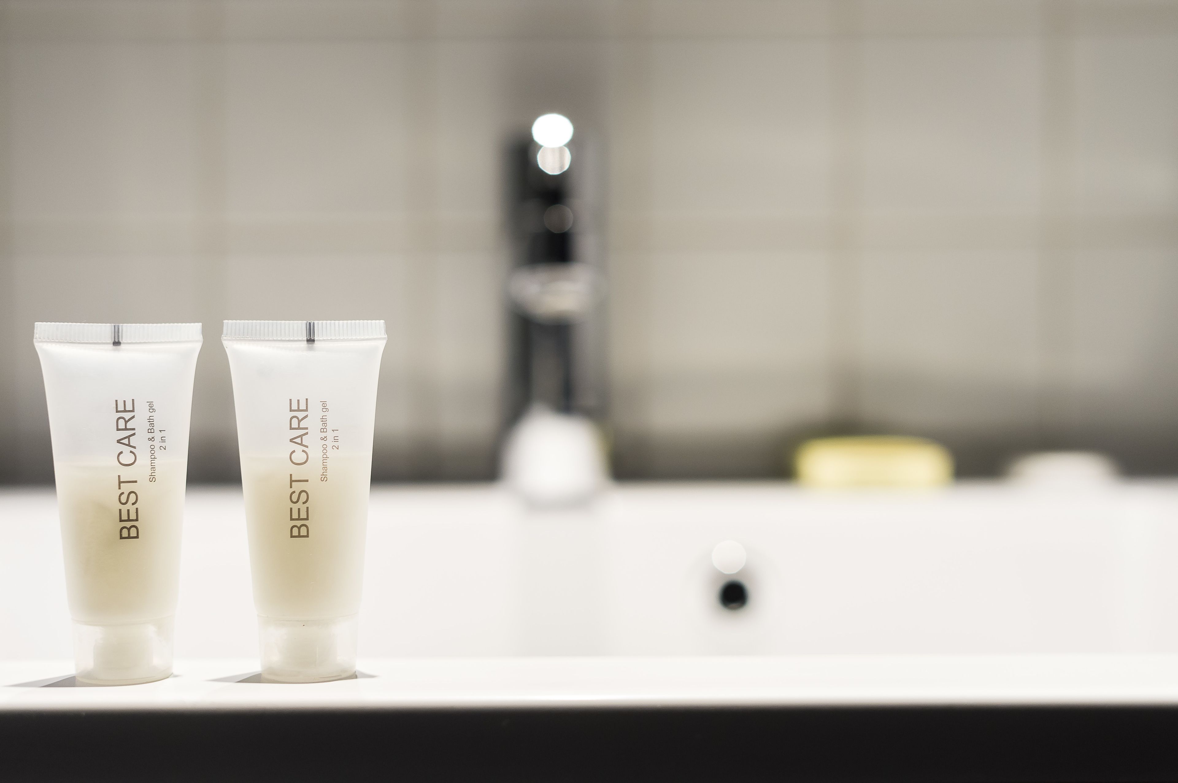 Two white Best Care shampoo and bath gel tubes on a bathroom counter.