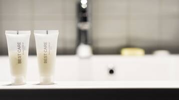 Dos tubos de champú y gel de baño Best Care blancos sobre una encimera de baño.