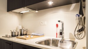A modern kitchen with a stainless steel sink, dark cabinets, and a white countertop. - Getaway Leuven (Leuven)