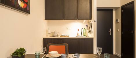 Un comedor con una mesa de madera oscura, sillas color naranja y una planta en maceta.