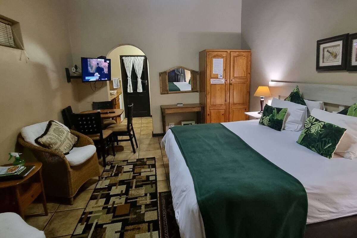 A hotel room with a bed, a chair, a desk, a television, and a wardrobe.