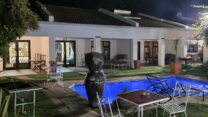 A house with a swimming pool, outdoor furniture, and a large potted plant.