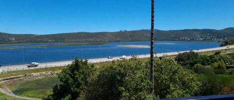A coastal view with a road, a body of water, and hills in the background.