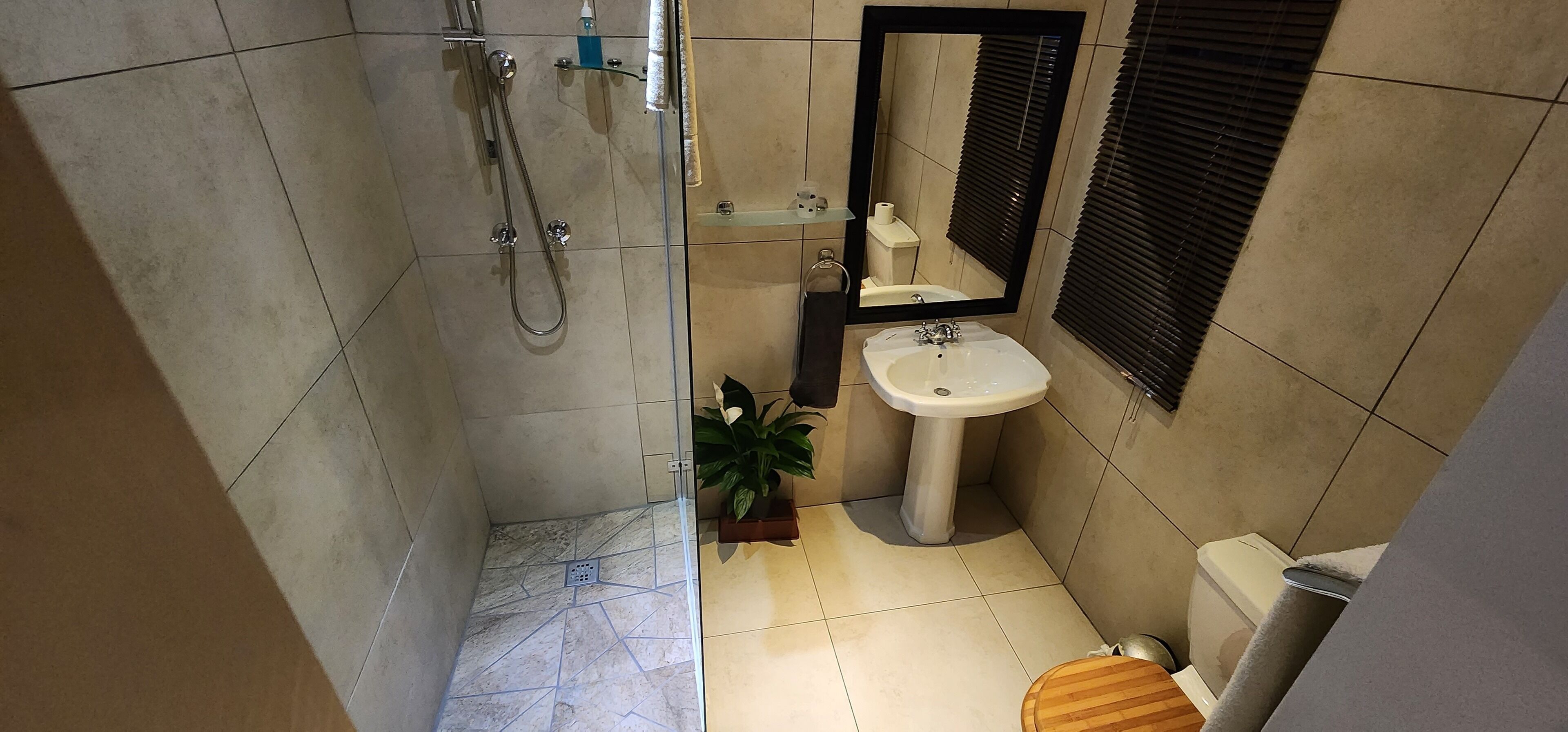 A compact bathroom with a shower, sink, toilet, and a mirror.