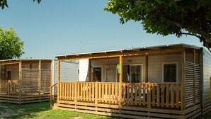 Une rangée de maisons mobiles dotées de terrasses et de porches en bois, chacune ayant une fenêtre et une porte.