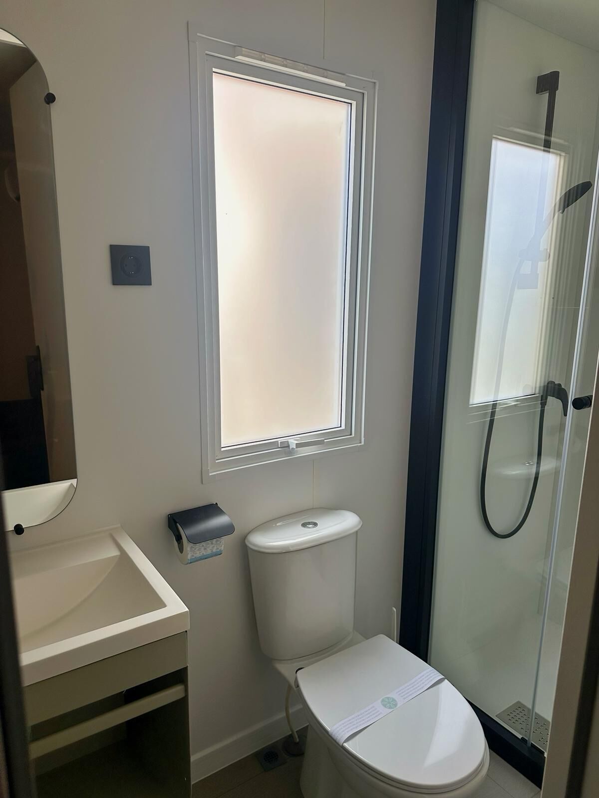 Ein Badezimmer mit Toilette, Waschbecken, Fenster und Dusche.