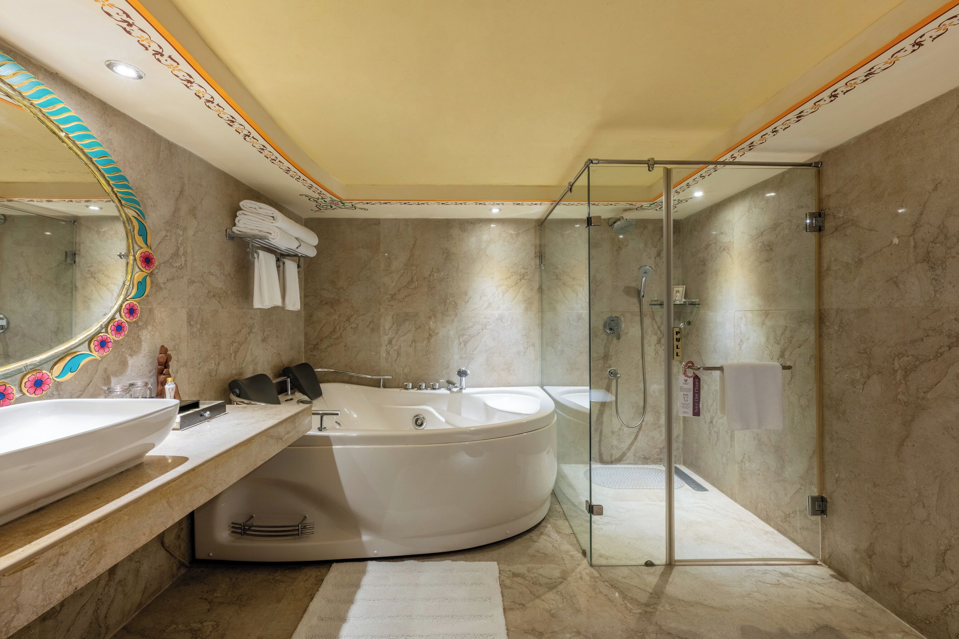Een moderne badkamer met een groot bad, een douchecabine met glazen wanden en een betegelde wand van marmer.